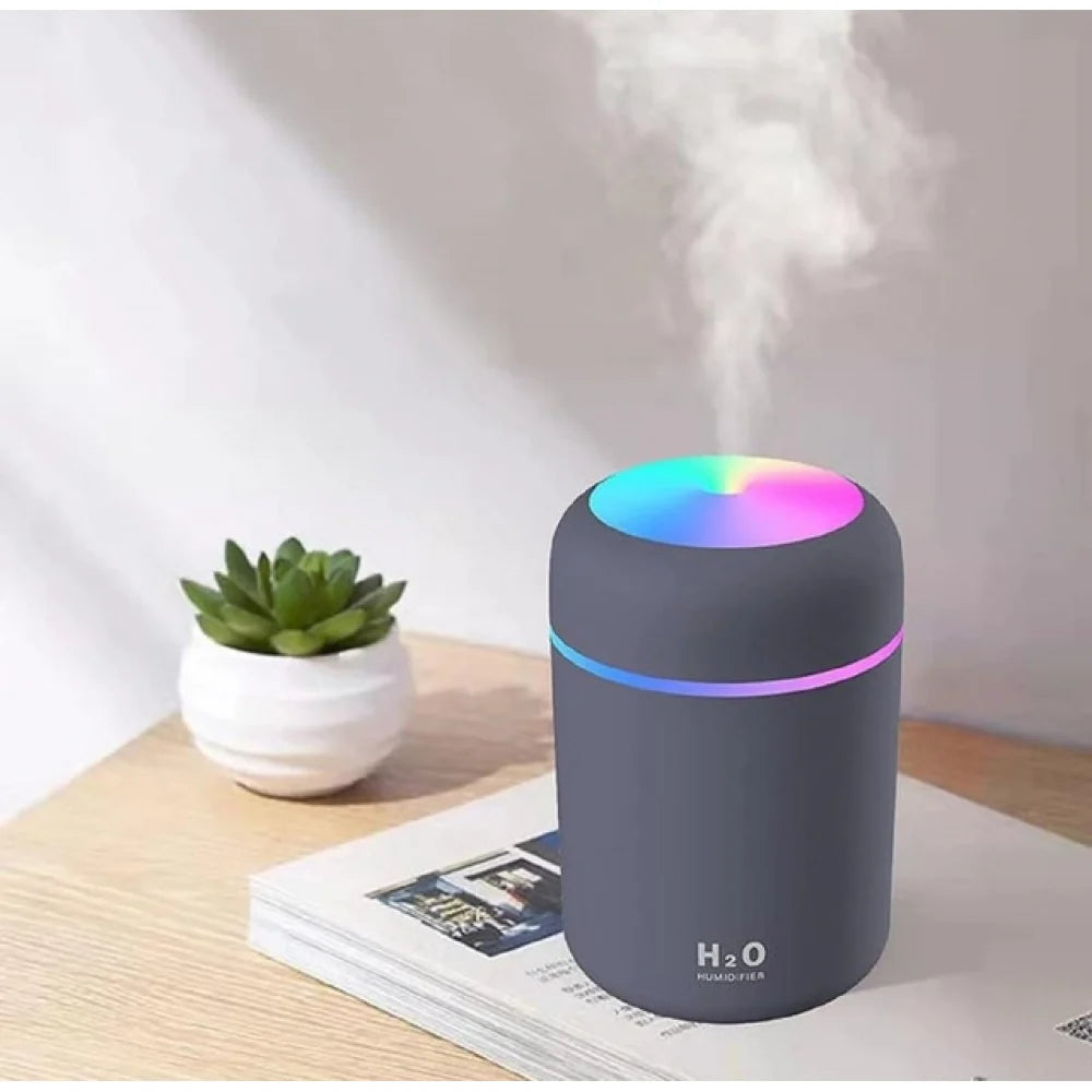 Grey mini humidifier with soft colour light on a bedside table